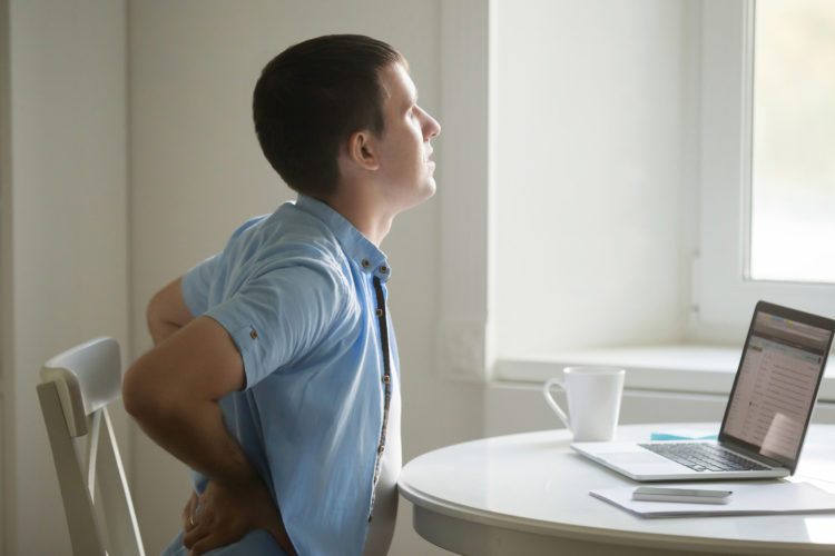 Man with back pain working at a laptop