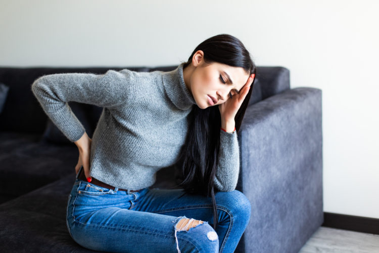 Woman with back pain sitting on the sofa